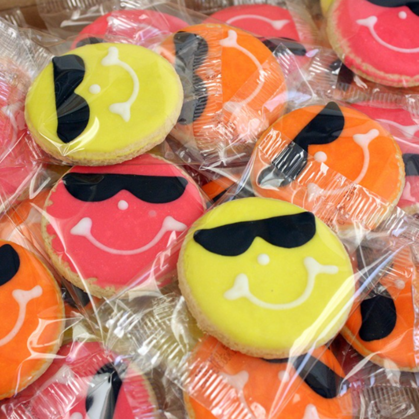 sweet smiley cookies decorated with sunglasses on pink, orange, and yellow round iced sugar cookies